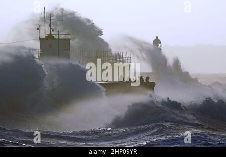 Die Wellen stürzen gegen die Meeresmauer und den Porthcawl Lighthouse in Porthcawl, Bridgend, Wales, ab, als der Sturm Eunice die Südküste trifft, wobei die Attraktionen schließen, die Reise gestört wird und in einigen Gebieten ein größerer Vorfall gemeldet wird, was bedeutet, dass die Menschen gewarnt werden, drinnen zu bleiben. Bilddatum: Freitag, 18. Februar 2022. Stockfoto