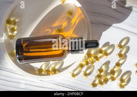 Flasche ätherisches Öl auf weißem Holztisch in hellem Sonnenlicht Stockfoto