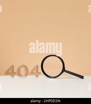 Schwarze Plastiklupe und 404 auf braunem Hintergrund. Konzeptseite nicht gefunden Stockfoto