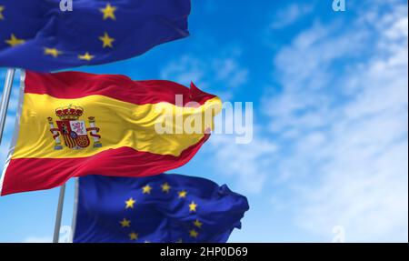 Die spanische Nationalflagge schwenkt zwischen zwei Flaggen der Europäischen Union mit blauem Himmel im Hintergrund. Internationale Beziehungen und europäische Diplomatie. Stockfoto