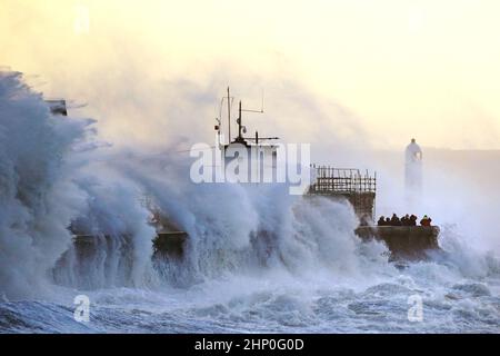 Die Wellen stürzen gegen die Meeresmauer und den Porthcawl Lighthouse in Porthcawl, Bridgend, Wales, ab, als der Sturm Eunice die Südküste trifft, wobei die Attraktionen schließen, die Reise gestört wird und in einigen Gebieten ein größerer Vorfall gemeldet wird, was bedeutet, dass die Menschen gewarnt werden, drinnen zu bleiben. Bilddatum: Freitag, 18. Februar 2022. Stockfoto