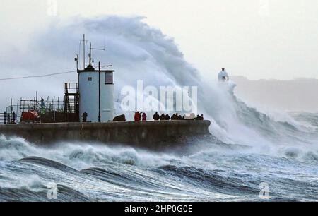 Die Wellen stürzen gegen die Meeresmauer und den Porthcawl Lighthouse in Porthcawl, Bridgend, Wales, ab, als der Sturm Eunice die Südküste trifft, wobei die Attraktionen schließen, die Reise gestört wird und in einigen Gebieten ein größerer Vorfall gemeldet wird, was bedeutet, dass die Menschen gewarnt werden, drinnen zu bleiben. Bilddatum: Freitag, 18. Februar 2022. Stockfoto