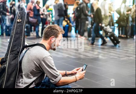 Abenteuerlicher Mann am internationalen Flughafen mit Handy - Wanderer Person am Terminal Gate wartet auf Flugzeug - Wanderlust Reise Reise-Con Stockfoto