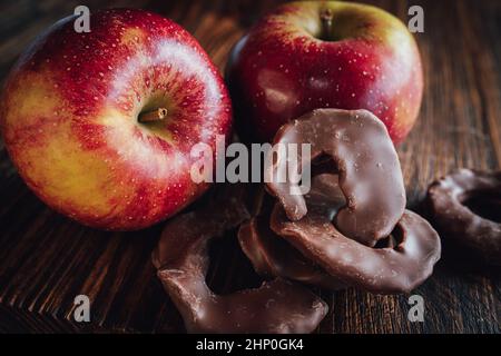 Winterapfel mit Schokoladenapfelringen auf dunklem Holz. Nahaufnahme mit Sweetes für Winter und weihnachten. Stockfoto