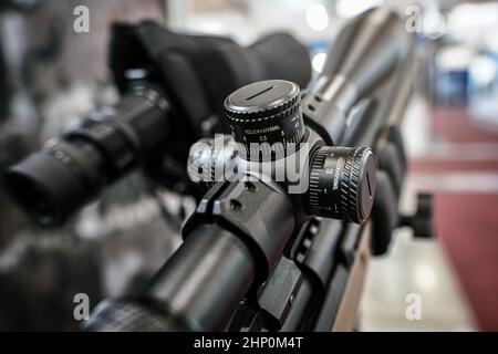 Schwarze Schießskop-Optik auf Gewehr montiert, die auf der Waffenmesse ausgestellt ist, Detailansicht der Einstellknöpfe. Stockfoto