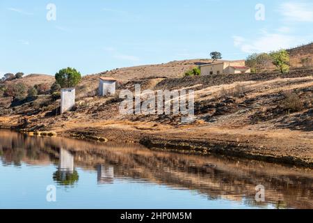 Landschaft mit kleinen Häusern, die sich im Rio Tinto widerspiegeln, einem Fluss, der durch die Provinz Huelva, Andalusien, Spanien fließt Stockfoto