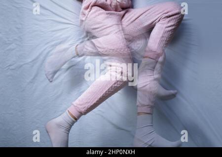 Afroamerikanische Frau mit RLS - Restless Legs Syndrom. Schlafen Im Bett Stockfoto