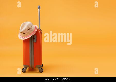 Strohhut Reisetaschen Koffer auf gelbem Hintergrund mit Kopierraum. Das Konzept der Sommerzeit, Urlaub, Tourismus. Stockfoto