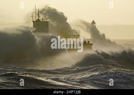 Die Wellen stürzen gegen die Meeresmauer und den Porthcawl Lighthouse in Porthcawl, Bridgend, Wales, ab, als der Sturm Eunice die Südküste trifft, wobei die Attraktionen schließen, die Reise gestört wird und in einigen Gebieten ein größerer Vorfall gemeldet wird, was bedeutet, dass die Menschen gewarnt werden, drinnen zu bleiben. Bilddatum: Freitag, 18. Februar 2022. Stockfoto
