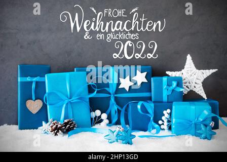 Deutsche Kalligraphie Frohe Weihnachten und ein glückliches 2022 bedeutet Frohe Weihnachten und Ein glückliches 2022. Türkisfarbenes Geschenk Mit Schleife Und Weihnachtsdekoration Stockfoto