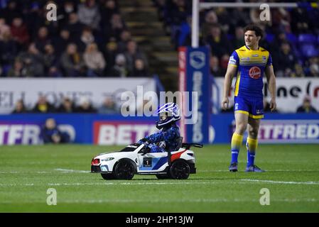 Der Spielball im Halliwell Jones Stadium wird von einem jungen Fahrer in einem Mini-BMW vor dem Spiel der Betfred Super League im Halliwell Jones Stadium, Warrington, geliefert. Warringtons erstes Heimspiel der Super League der Saison wurde am Donnerstagabend unter amüsanten Umständen verschoben, als Whizzy Rascal den Namen aufgab. Anstatt direkt zum Anstoßpunkt zu fahren, steuerte der Fahrer auf die andere Seite des Platzes und nachdem er zum Umdrehen ermutigt wurde, entschied er sich, dass es dann mehr Spaß machen würde, auf die entgegengesetzte Touchline weiterzufahren. Bilddatum: Donnerstag, 17. Februar 2022. Stockfoto