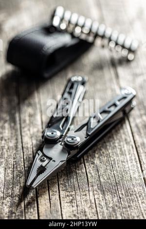 Multi-Tools-Zange mit anderen Werkzeugen und Messer. Multifunktionszange auf Holztisch. Stockfoto