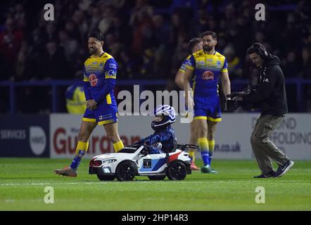 Der Spielball im Halliwell Jones Stadium wird von einem jungen Fahrer in einem Mini-BMW vor dem Spiel der Betfred Super League im Halliwell Jones Stadium, Warrington, geliefert. Warringtons erstes Heimspiel der Super League der Saison wurde am Donnerstagabend unter amüsanten Umständen verschoben, als Whizzy Rascal den Namen aufgab. Anstatt direkt zum Anstoßpunkt zu fahren, steuerte der Fahrer auf die andere Seite des Platzes und nachdem er zum Umdrehen ermutigt wurde, entschied er sich, dass es dann mehr Spaß machen würde, auf die entgegengesetzte Touchline weiterzufahren. Bilddatum: Donnerstag, 17. Februar 2022. Stockfoto
