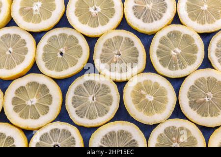 Viele frische, saftige Zitronenscheiben auf blauem Stoffhintergrund, Draufsicht Stockfoto