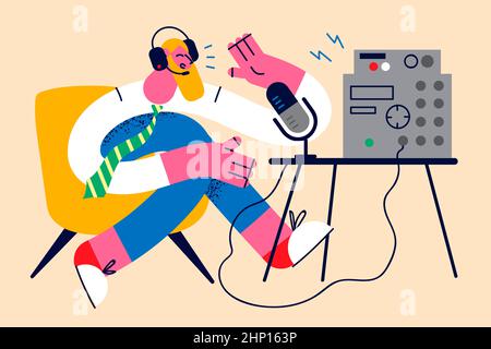 Lächelnder Mann in Kopfhörern reden im Radio am Mikrofon haben Sitzung mit den Zuhörern. Fröhlicher männlicher Moderator oder Moderator sprechen auf einem Podcast auf dem Mikrofon in der Luft. Live b Stockfoto