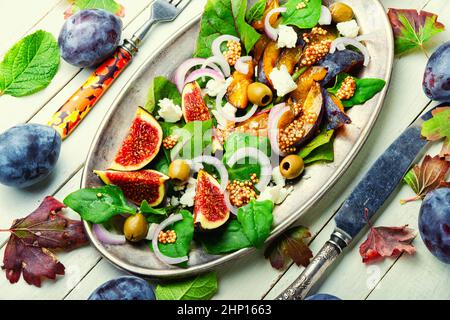 Herbstsalat mit Pflaumen, Feigen und Oliven.Sommersalat mit Früchten und Nüssen. Stockfoto