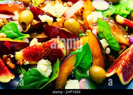 Salat mit Pflaumen, Feigen, Oliven und Feta-Käse.Herbstsalat mit Früchten und Grün.Nahaufnahme Stockfoto