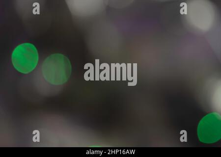 Abstrakter Bokeh-Hintergrund. Unscharf verwischte weiße und grüne Farbe hell auf dunklem Hintergrund Stockfoto
