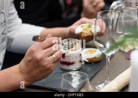 Frau isst Dessert in einer Glastasse, mit Jello, Joghurt und Belag in einem Restaurant serviert. Kleine Desserts Stockfoto