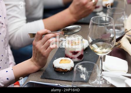 Frau isst Dessert in einer Glastasse, mit Jello, Joghurt und Belag in einem Restaurant serviert. Kleine Desserts Stockfoto