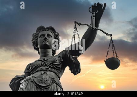 Symbol der Justizia-Figur in Frankfurt mit dramatischem Sonnenaufgangshintergrund Stockfoto