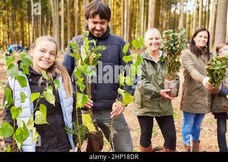 Familie und Förster im Wald mit Baumkeimlingen für nachhaltige ökologische Wiederaufforstung Stockfoto
