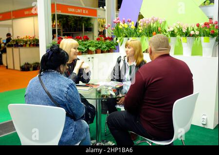 Menschen, die in einer Lounge-Zone zwischen Blumensträußen sitzen und miteinander kommunizieren. 17. April 2019. Ausstellung Flower Expo Ukraine. Kiew, Ukraine Stockfoto