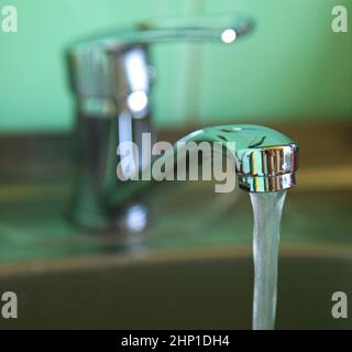 Wasser fließt aus dem Wasserhahn. Wasserhahn mit Wasser, das in die Küchenspüle fließt. Tarife und Preiserhöhungen für Wasser. Gefährliches Wasser Stockfoto