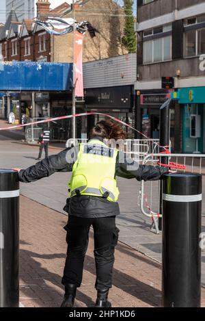 Southend on Sea, Essex, Großbritannien. 18th. Februar 2022. Der Sturm Eunice hat Southend on Sea erreicht und Schäden an Gebäuden in der High Street und Umgebung verursacht. Straßenranger versuchen, die Menschen fernzuhalten. Ein zerschmettert Fenster oben hat Glas auf die Straße fallen gelassen. Teile der High Street wurden seitdem aufgrund von Verletzungen von Bürgern geschlossen. Weibliche Sicherheitsbeauftragte der Gemeinschaft, die sich gegen die Sturmwinde mit Pollern zur Verankerung ausstrebe Stockfoto