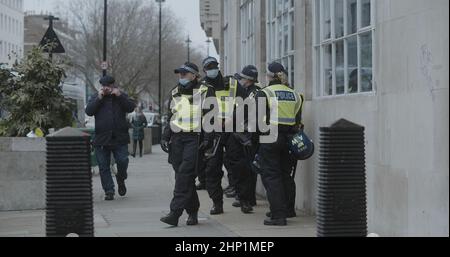 London, Großbritannien - 01 22 2022: Eine Gruppe von Männern und Frauen traf Polizisten, die Gesichtsmasken trugen, auf dem Bürgersteig am Portland Place. Stockfoto