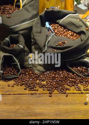 Kaffeebohnen auf Taschen über rustikale Holz Hintergrund Stockfoto