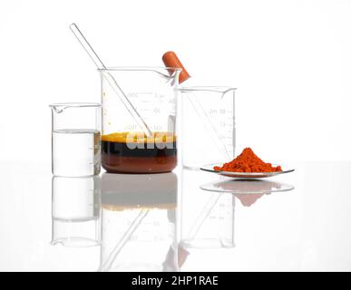 Bleioxid (II,IV) im chemischen Uhrglas neben kristallklare Flüssigkeit und eisenhaltige Chlorid-Flüssigkeit mit Rührstab im Becher platzieren. Nahaufnahme Chemikalie Stockfoto