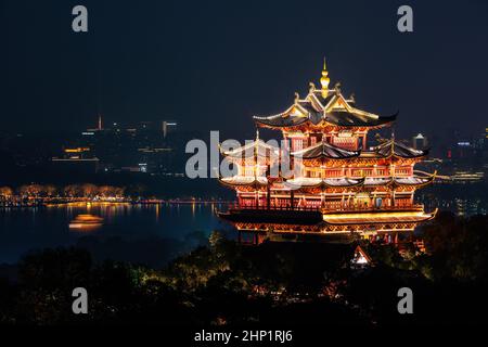 Nacht Blick auf das beleuchtete Cheng Huang Ge (Stadt Gottes Pavillion) mit West Lake und die Skyline der Stadt im Hintergrund, Hangzhou, China Stockfoto