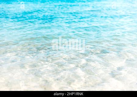 Nahaufnahme des kristallklaren türkisfarbenen Meeres und der weichen blauen Wellen des Ozeans, weißer Schaum am goldenen Sandstrand der tropischen Insel, Urlaub Borde Stockfoto