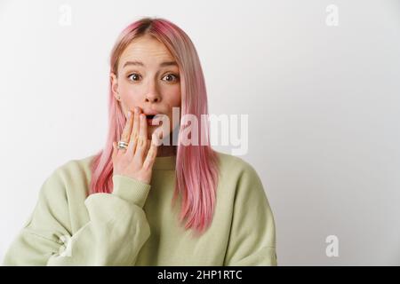 Junge, überraschte Frau, die ihren Mund bedeckt und isoliert auf weißen Hintergrund auf die Kamera schaut Stockfoto