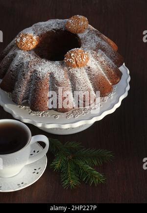 Schokoladenkuchen mit Puderzucker und Kaffeetasse. Weihnachten Hintergrund . Stockfoto