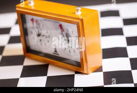 Die klassische, mechanische Schachuhr auf Holzschachbrett. Selektiver Fokus Stockfoto