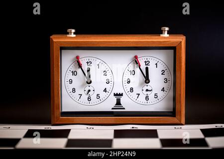 Die klassische, mechanische Schachuhr auf Holzschachbrett. Selektiver Fokus Stockfoto