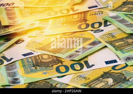 Haufen von europäischem Geld im Sonnenlicht. 100 Euro Hintergrund. Selektiver Fokus. Stockfoto