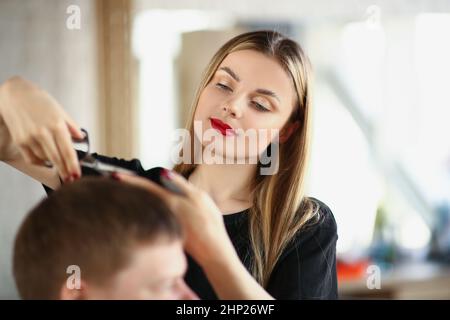 Eine schöne Frau schneidet einem Mann die Haare mit einer Schere, Nahaufnahme Stockfoto