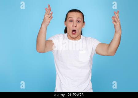 Emotionen eines Fernsehfans. Schreie, Hass, Wut. Weinender emotionaler wütender junger Mann schreit auf blauem Hintergrund. Mann unterstützt Team Stockfoto