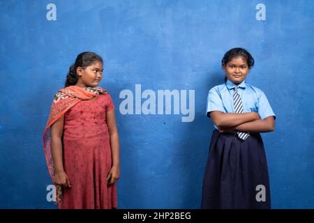 Trauriges Kind, das sich selbst in lächelndem Schulkleid oder Unifrom ansieht - Konzept des Kindes, das von Bildung, benachteiligter Schulbildung und Armut träumt. Stockfoto