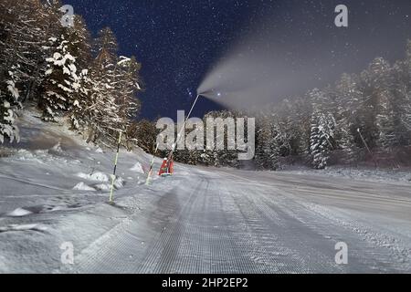 Skilift in den Alpen bei Nacht mit Sternenhimmel oben, Schneekanone bei der Arbeit, Skigebiet Les Orres 1800 Stockfoto