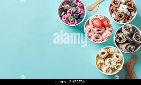 Gerolltes Eis in Kegelbecher auf blauem Hintergrund. Verschiedene Eisrollen Draufsicht oder flaches Lay. Thai Stil gerolltes Eis mit Kopierraum für Text oder Stockfoto