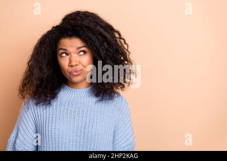 Foto von jungen hübschen Frau aussehen leeren Raum unzufrieden nachdenklich isoliert über beige Farbe Hintergrund Stockfoto