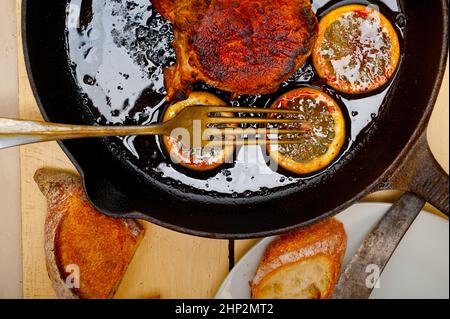 Schweinekotelett auf eisernen Pfanne mit Zitrone und Gewürze Gewürz angebraten Stockfoto