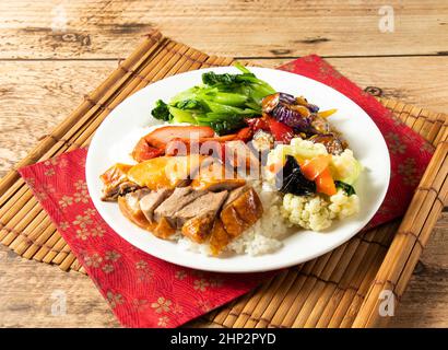 Three Treasures chinesischer Reis mit Salat in weißem Teller auf Matte isoliert auf Holzhintergrund Draufsicht chinesischer Reis Stockfoto