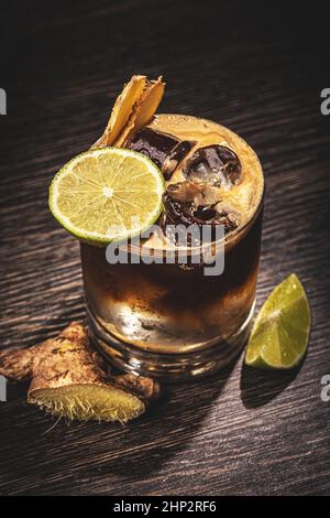 Glas Cola mit Limette, Ingwer und Eis auf Holzboden Stockfoto