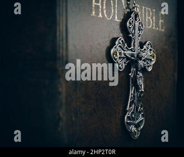 Eine Nahaufnahme einer verzierten antiken Rosenkranzkette, die auf einer alten, abgenutzten antiken bibel auf einem dunklen, isolierten Hintergrund hängt - 3D Render Stockfoto