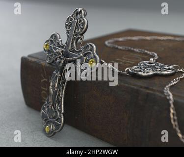 Eine Nahaufnahme einer kunstvollen antiken Rosenkranzkette neben einer alten getragenen antiken bibel auf einem isolierten Hintergrund - 3D Render Stockfoto